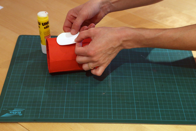 Klebe den weißen Bogen nun auf die Tetrapackung. Lass dabei etwa 4 cm Abstand zum oberen Rand.