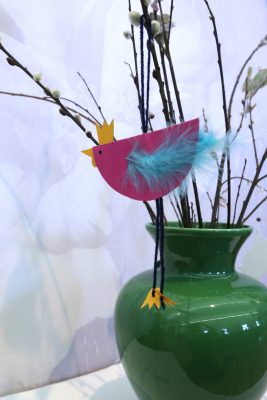Dekohuhn: Der Körper ist ein Halbkreis aus buntem Papier, Kamm, Schnabel und Füße sind aus gelbem Papier ausgeschnitten. Die Flügel sind mit Kunstfedern gestaltet.