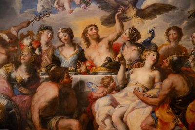 Farbiges Gemälde mit Frauen und Männer um einen reichich gedeckten Tisch bei einem Fest